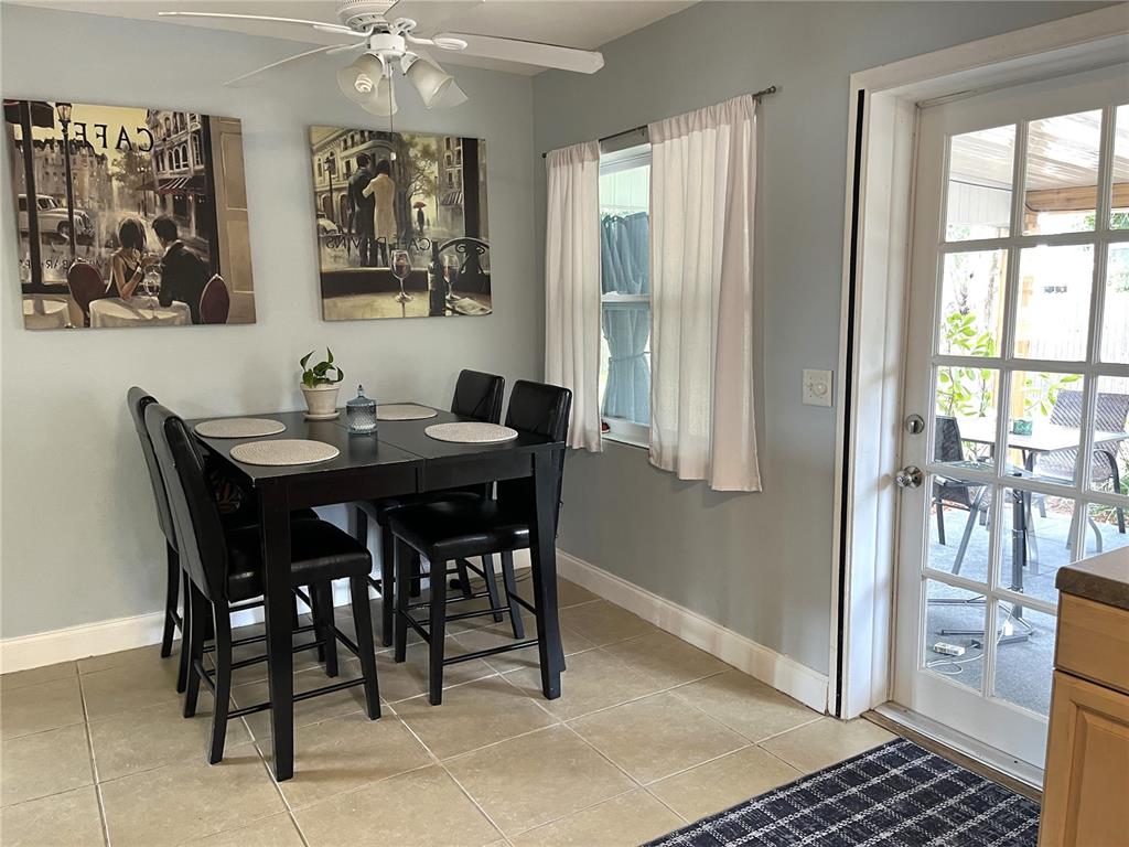 A dining area features a dark table with four chairs, wall art, and a glass door — 1358 N LOTUS DRIVE, DUNEDIN, FL
