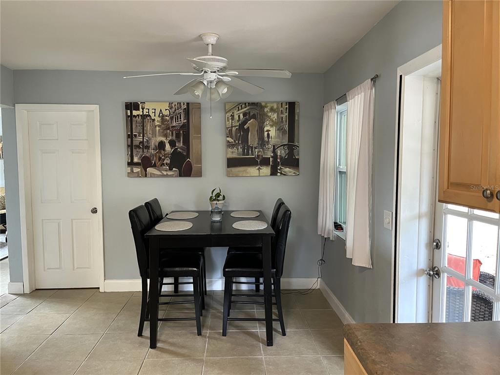A dining area features a black table with four chairs, wall art, and a ceiling fan — 1358 N LOTUS DRIVE, DUNEDIN, FL
