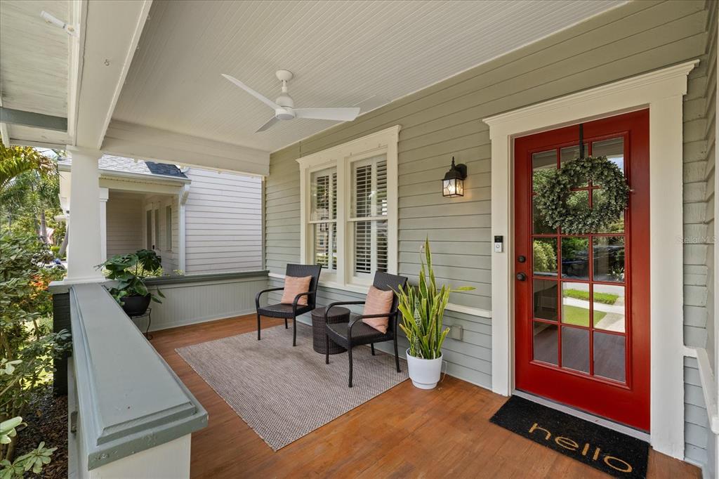 A covered front porch features a red door, two chairs, a rug, and a ceiling fan — 3410 W SANTIAGO STREET, TAMPA, FL