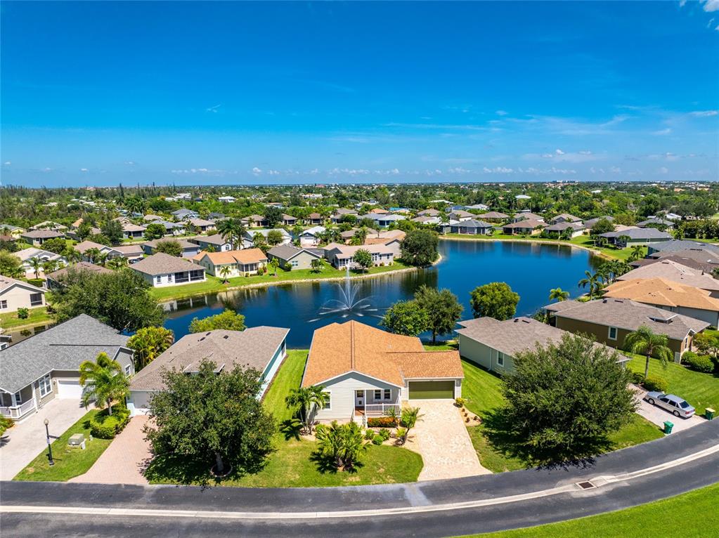 An aerial view shows a suburban house with a fountain in the backyard lake — 24819 RIO VILLA LAKES CIRCLE, PUNTA GORDA, FL