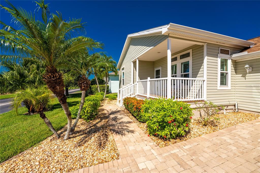 A light-colored house with a front porch, palm trees, and a paved walkway — 24819 RIO VILLA LAKES CIRCLE, PUNTA GORDA, FL