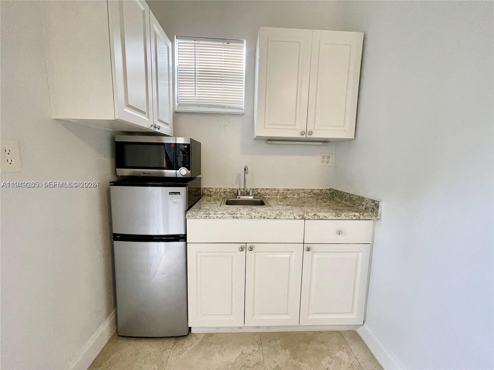 A small kitchenette features white cabinets, a granite countertop, a sink, and a mini-fridge — 712 SW 5th Ct # 3, Hallandale Beach FL 33009, HALLANDALE BEACH, FL