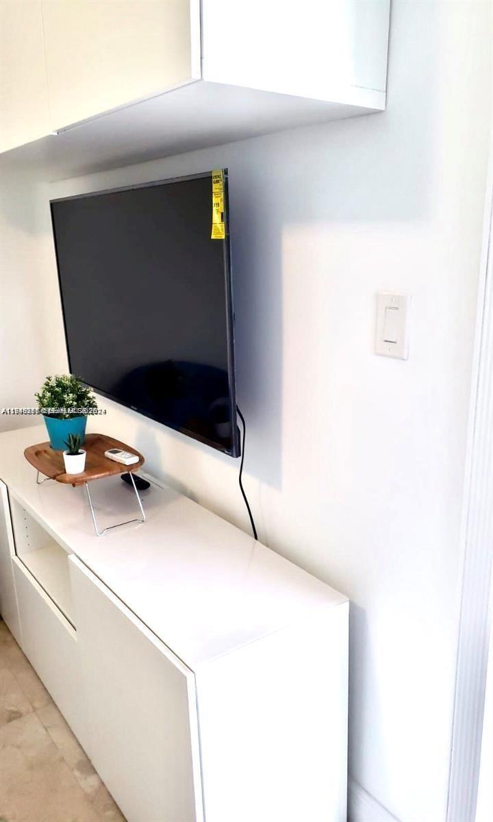 A wall-mounted television sits above a white cabinet with a small potted plant — 712 SW 5th Ct # 3, Hallandale Beach FL 33009, HALLANDALE BEACH, FL