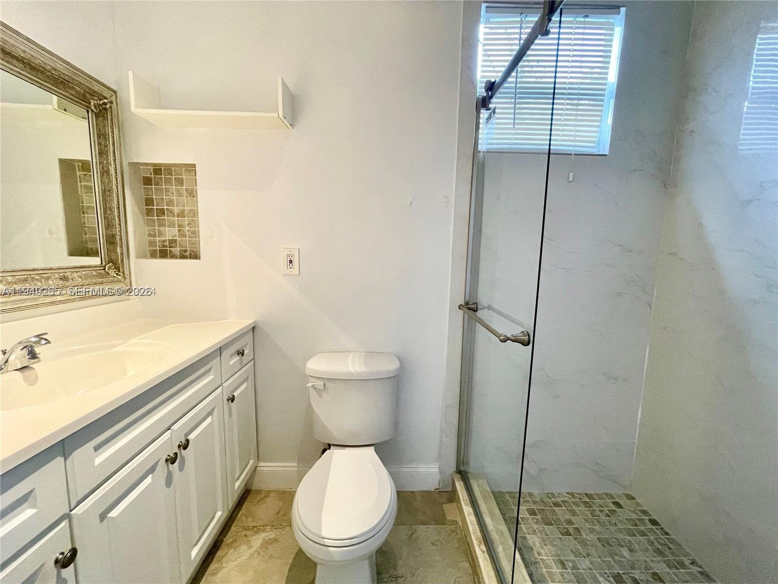 A bathroom features a white vanity, a toilet, and a glass-enclosed shower with tiled floors — 712 SW 5th Ct # 3, Hallandale Beach FL 33009, HALLANDALE BEACH, FL