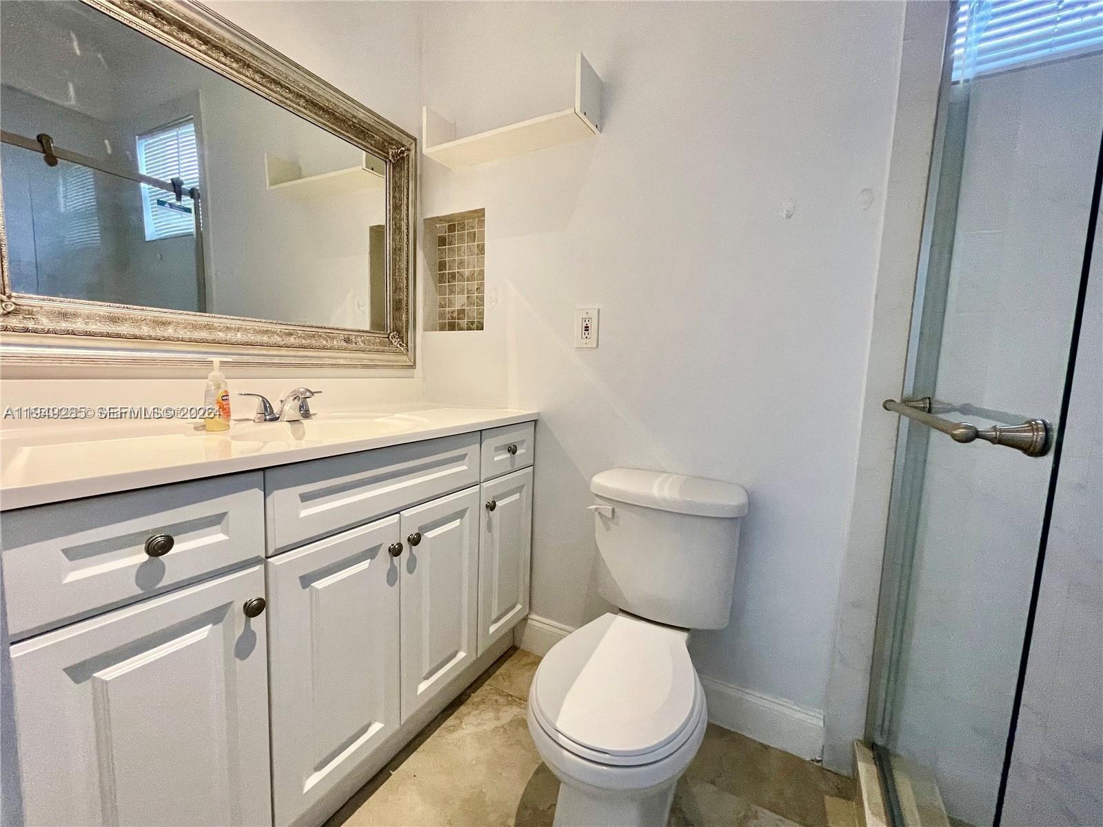A bathroom features a white vanity, a framed mirror, a toilet, and a glass shower — 712 SW 5th Ct # 3, Hallandale Beach FL 33009, HALLANDALE BEACH, FL