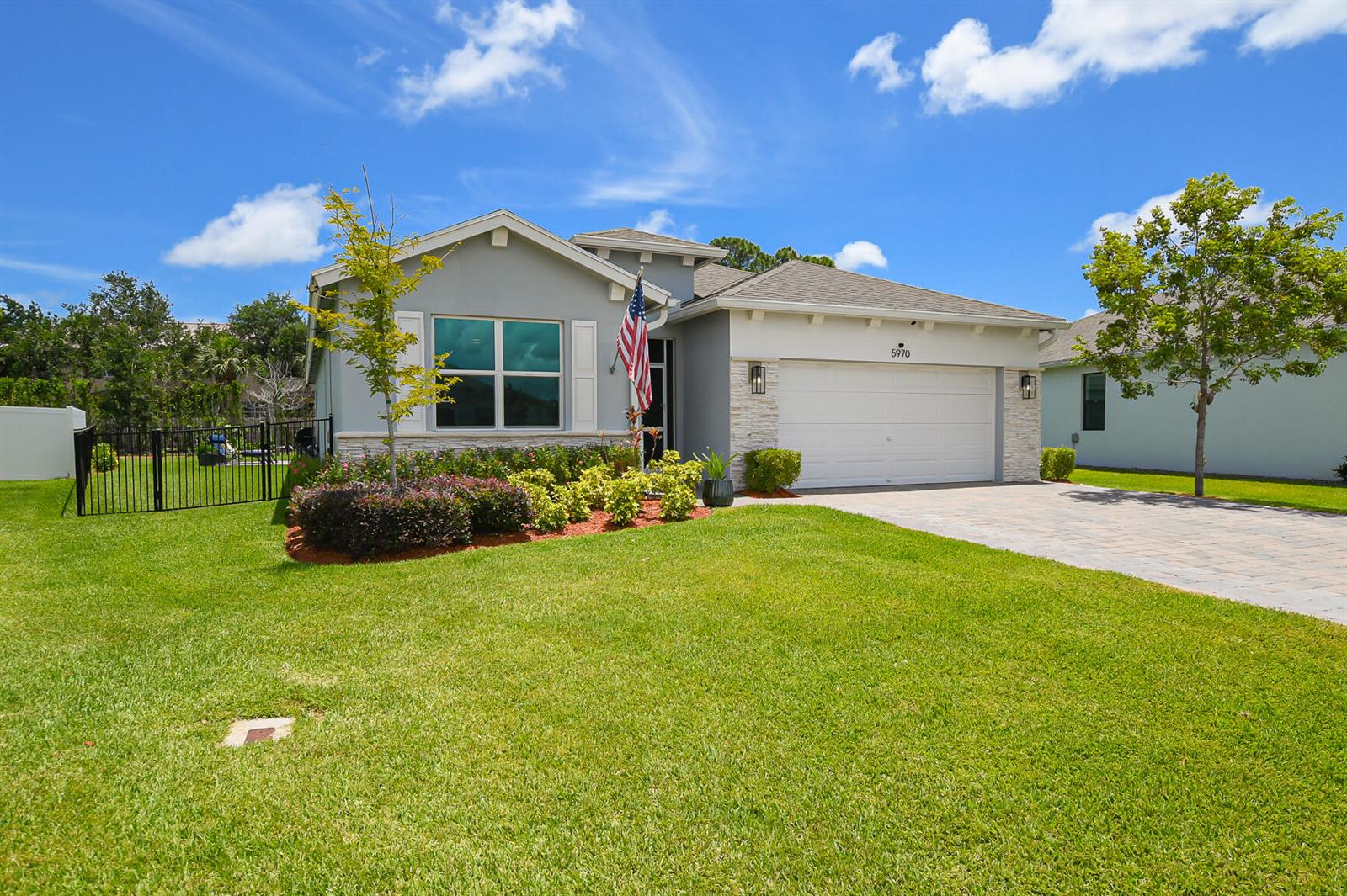 A single-story house with a gray exterior, stone accents, a two-car garage, and a lawn — 5970 SE Skyblue Circle, Stuart FL 34997, STUART, FL