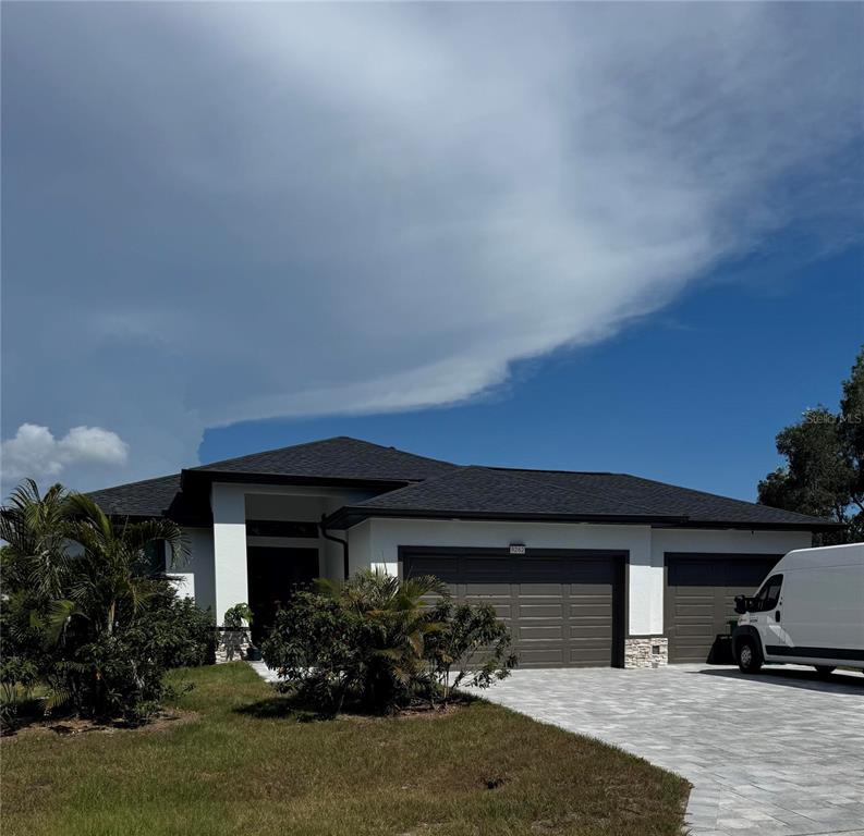 A single-story house with a white exterior, dark roof, and a paved driveway — 9262 GENESEE STREET, PORT CHARLOTTE, FL