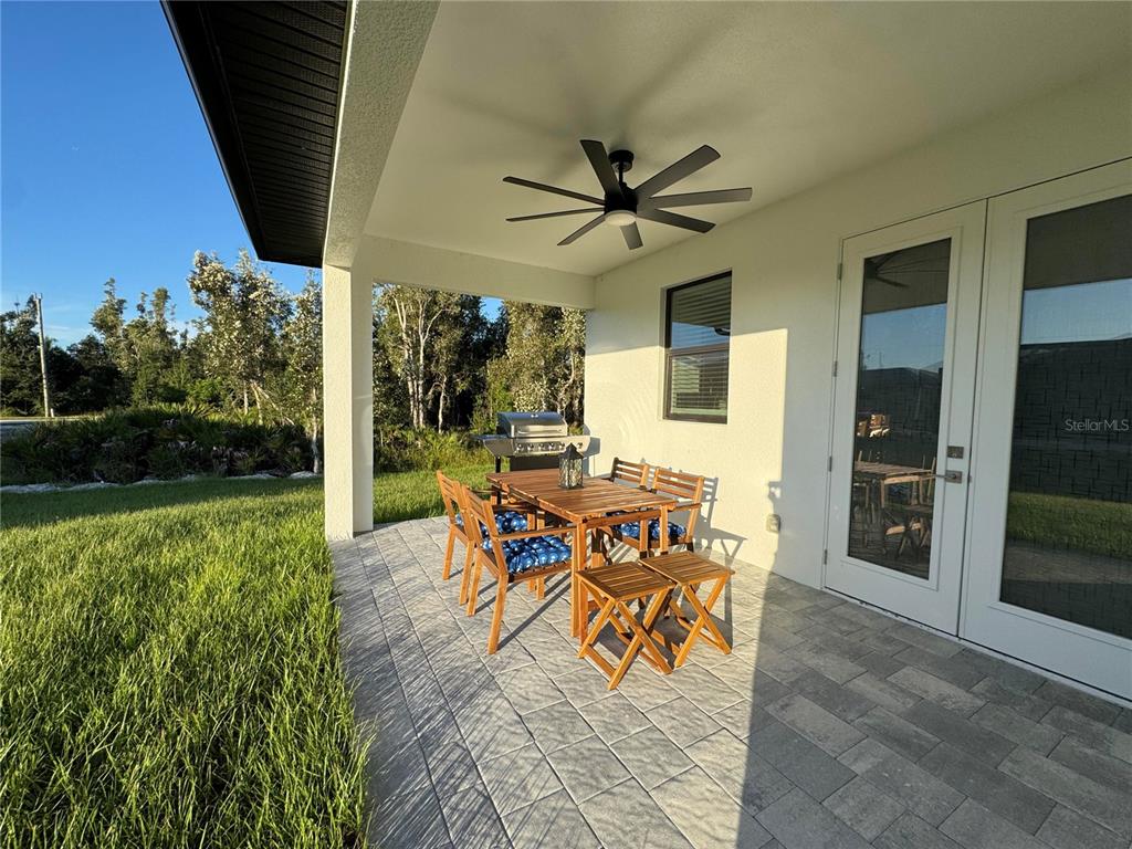 A covered patio features a dining set, a grill, and a ceiling fan — 9262 GENESEE STREET, PORT CHARLOTTE, FL