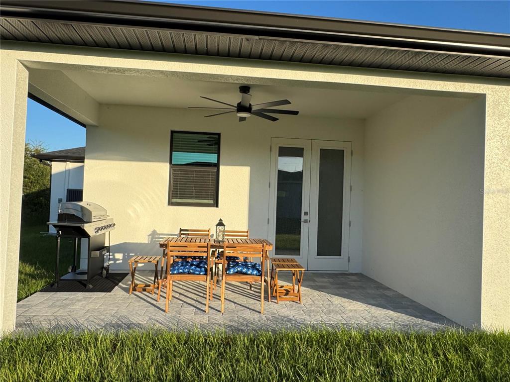 A covered patio features a paver floor, a ceiling fan, a grill, and dining furniture — 9262 GENESEE STREET, PORT CHARLOTTE, FL