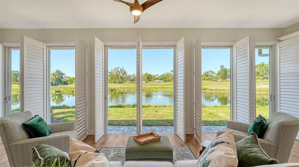 A sunroom with two armchairs and a view of a pond and golf course — 4060 PENSHURST PARK, SARASOTA, FL