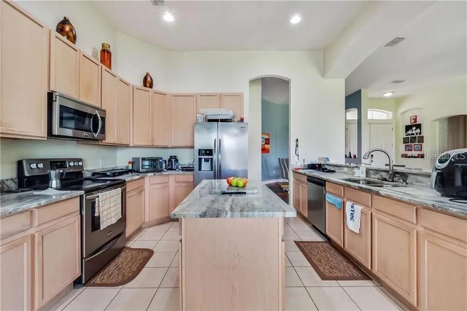 A kitchen with light wood cabinets, stainless steel appliances, and a central granite-topped island — 2630 CAPTAINS COURT, KISSIMMEE, FL