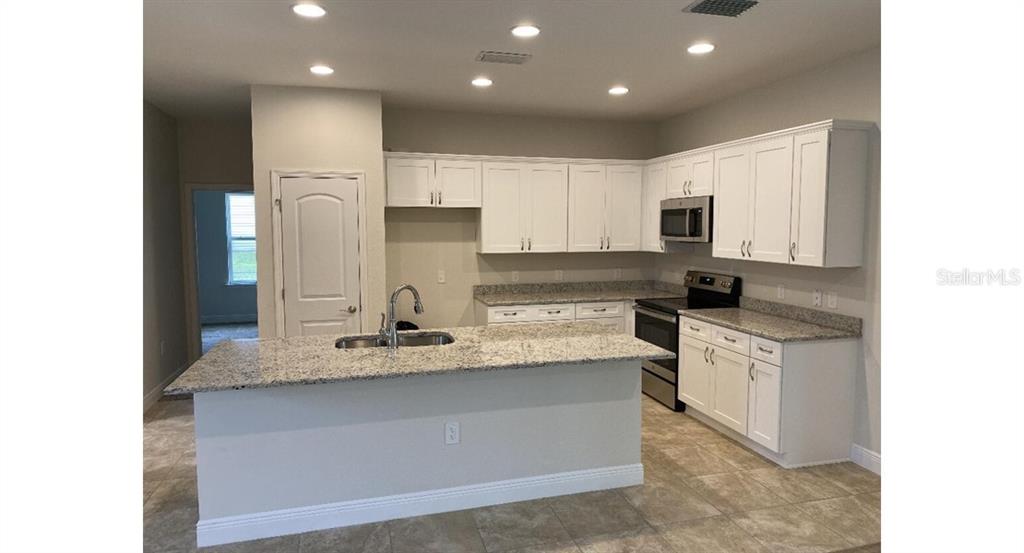 A kitchen with white cabinets, granite countertops, a center island, and stainless steel appliances — 3843 SAN MATEO DRIVE, NORTH PORT, FL