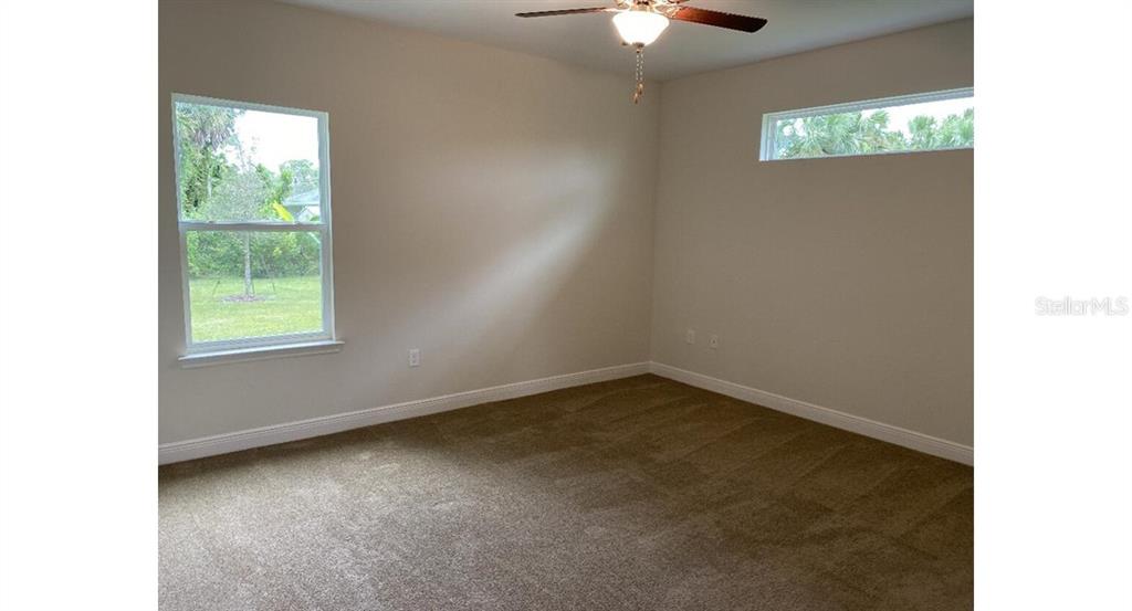 A carpeted bedroom features a ceiling fan, a standard window, and a high horizontal window — 3843 SAN MATEO DRIVE, NORTH PORT, FL