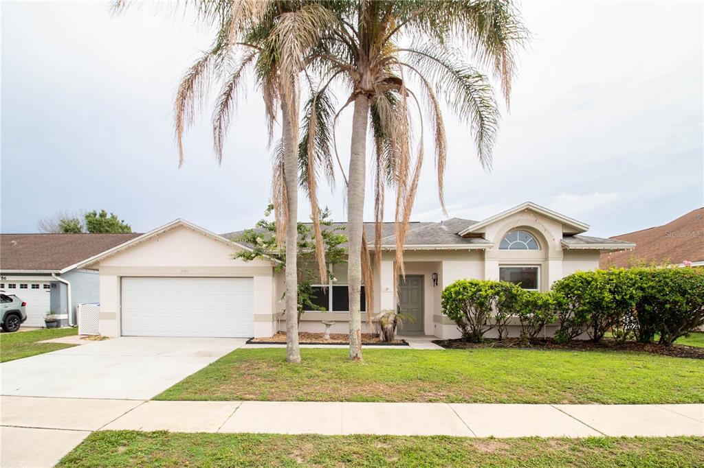 A single-story suburban house with a two-car garage, palm trees, and a landscaped front yard — 2782 PICADILLY CIRCLE, KISSIMMEE, FL