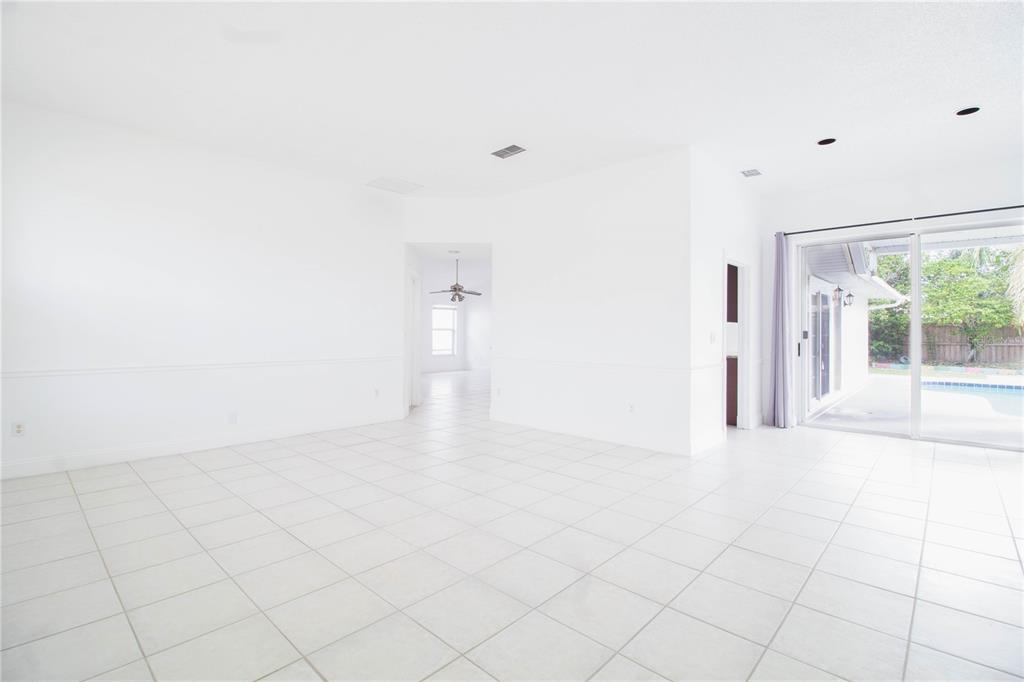 A bright, empty room with white tile floors, white walls, and sliding glass patio doors — 2782 PICADILLY CIRCLE, KISSIMMEE, FL