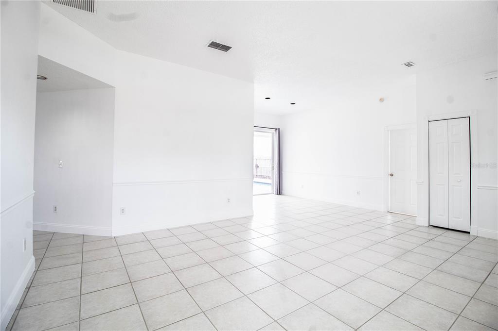 A bright, empty room features white walls, tile flooring, and a sliding glass door — 2782 PICADILLY CIRCLE, KISSIMMEE, FL