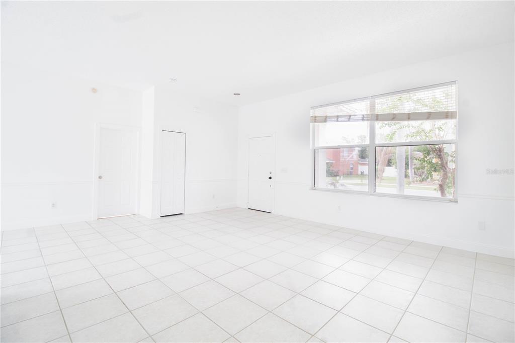 An empty room with white walls, tiled floors, and a large window overlooking the street — 2782 PICADILLY CIRCLE, KISSIMMEE, FL