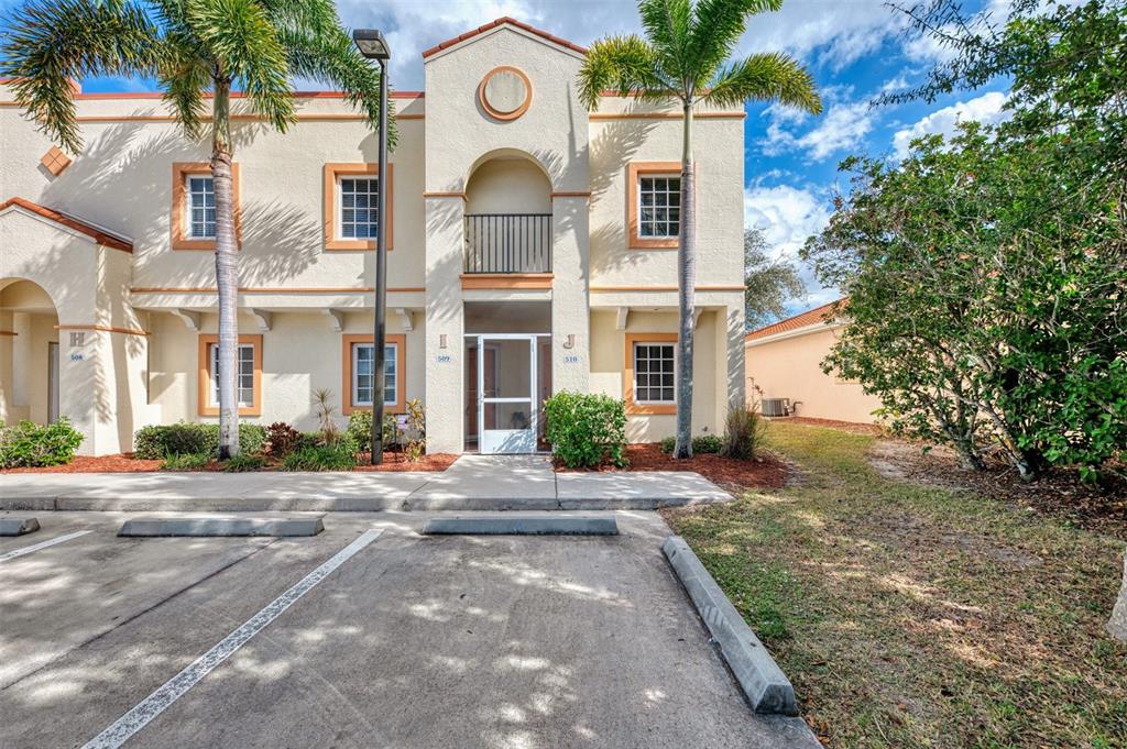 A two-story stucco apartment building with palm trees and a paved parking lot in front — 1246 RIO DE JANEIRO AVENUE UNIT 510, PUNTA GORDA, FL
