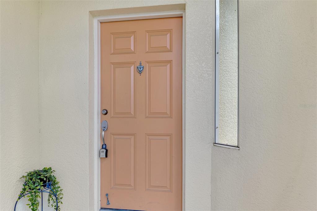 A peach-colored front door with a silver handle and a lockbox sits on a porch — 1246 RIO DE JANEIRO AVENUE UNIT 510, PUNTA GORDA, FL