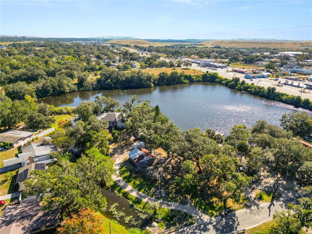 An aerial view shows a house and a small shed situated beside a lake — 109 NE 4TH AVENUE, MULBERRY, FL