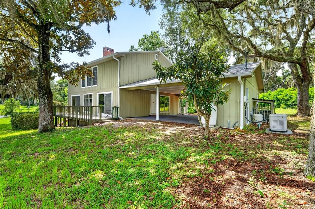 The exterior of a two-story house features green vertical siding, a deck, and a carport — 1980 LAKE HIRES ROAD, DE LEON SPRINGS, FL