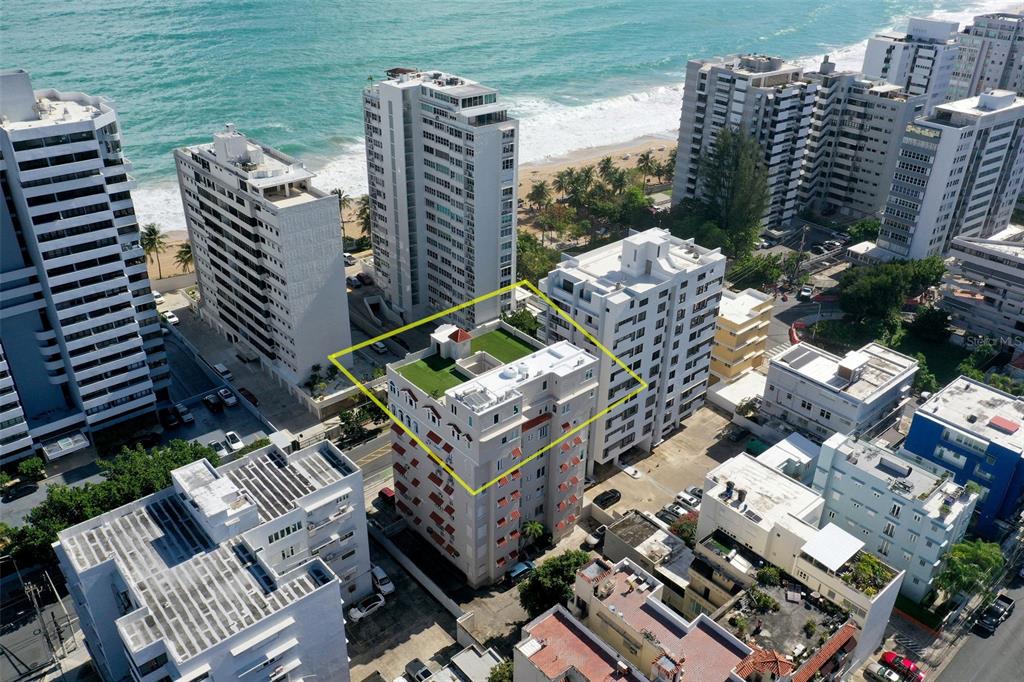 An aerial view of a multi-story apartment building with a rooftop terrace near the beach — 1506 ASHFORD UNIT 402, SAN JUAN, PR