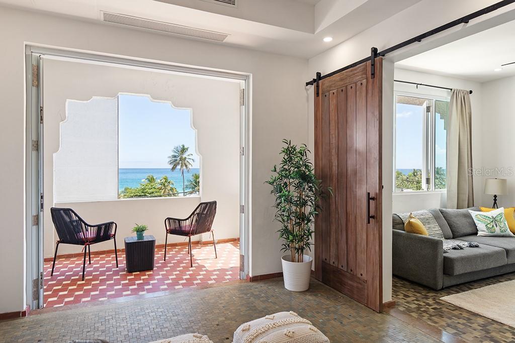 A balcony with ocean views and two chairs sits beside a room with a sliding door — 1506 ASHFORD UNIT 402, SAN JUAN, PR