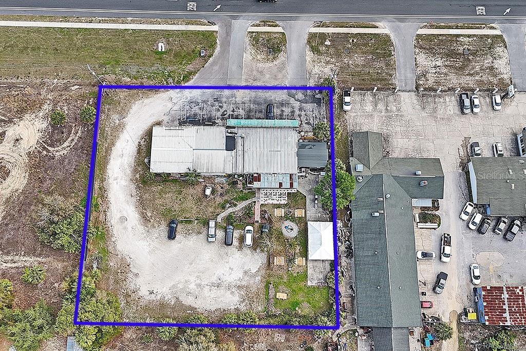An aerial view shows a commercial building with a large gravel parking lot and driveway — 4828 S SUNCOAST BOULEVARD, HOMOSASSA, FL