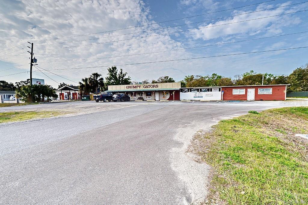 A low-slung commercial building with a Grumpy Gators sign sits behind a large gravel lot — 4828 S SUNCOAST BOULEVARD, HOMOSASSA, FL