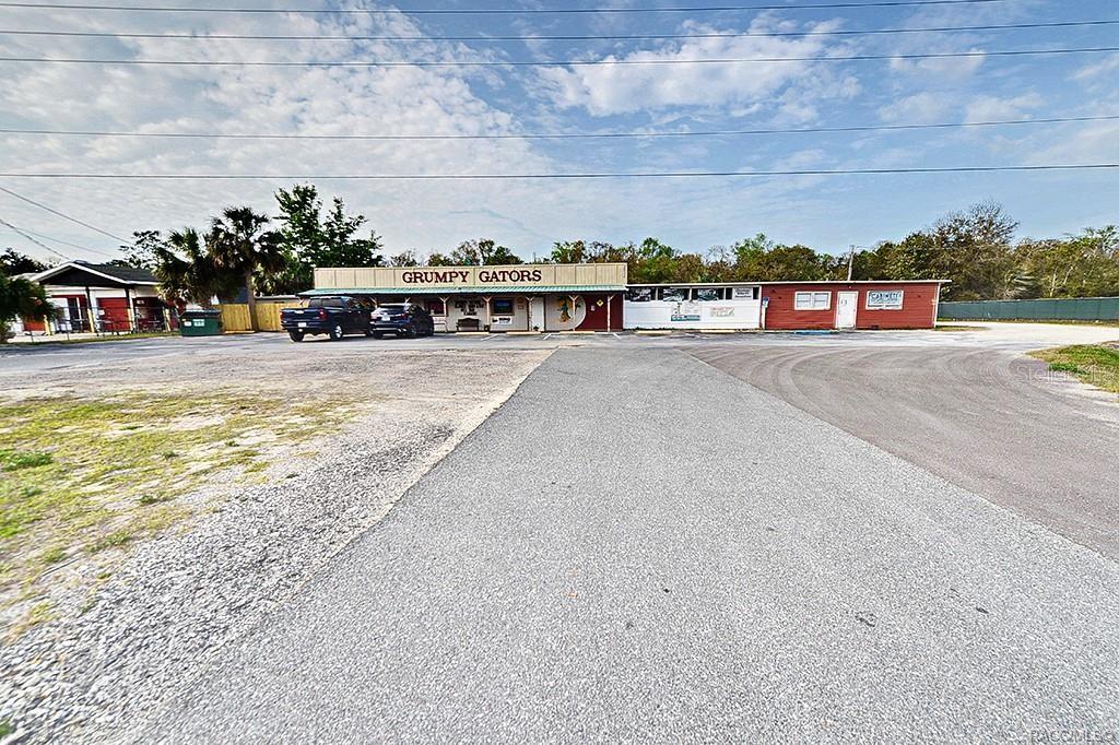 A one-story commercial building with a red and beige exterior features the sign Grumpy Gators — 4828 S SUNCOAST BOULEVARD, HOMOSASSA, FL