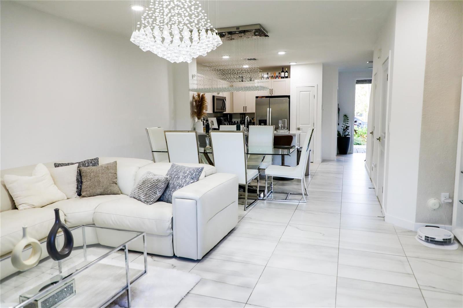 A white living room and dining area with tile floors and a crystal chandelier — 148 SE 5th Court, Deerfield Beach FL 33441, DEERFIELD BEACH, FL