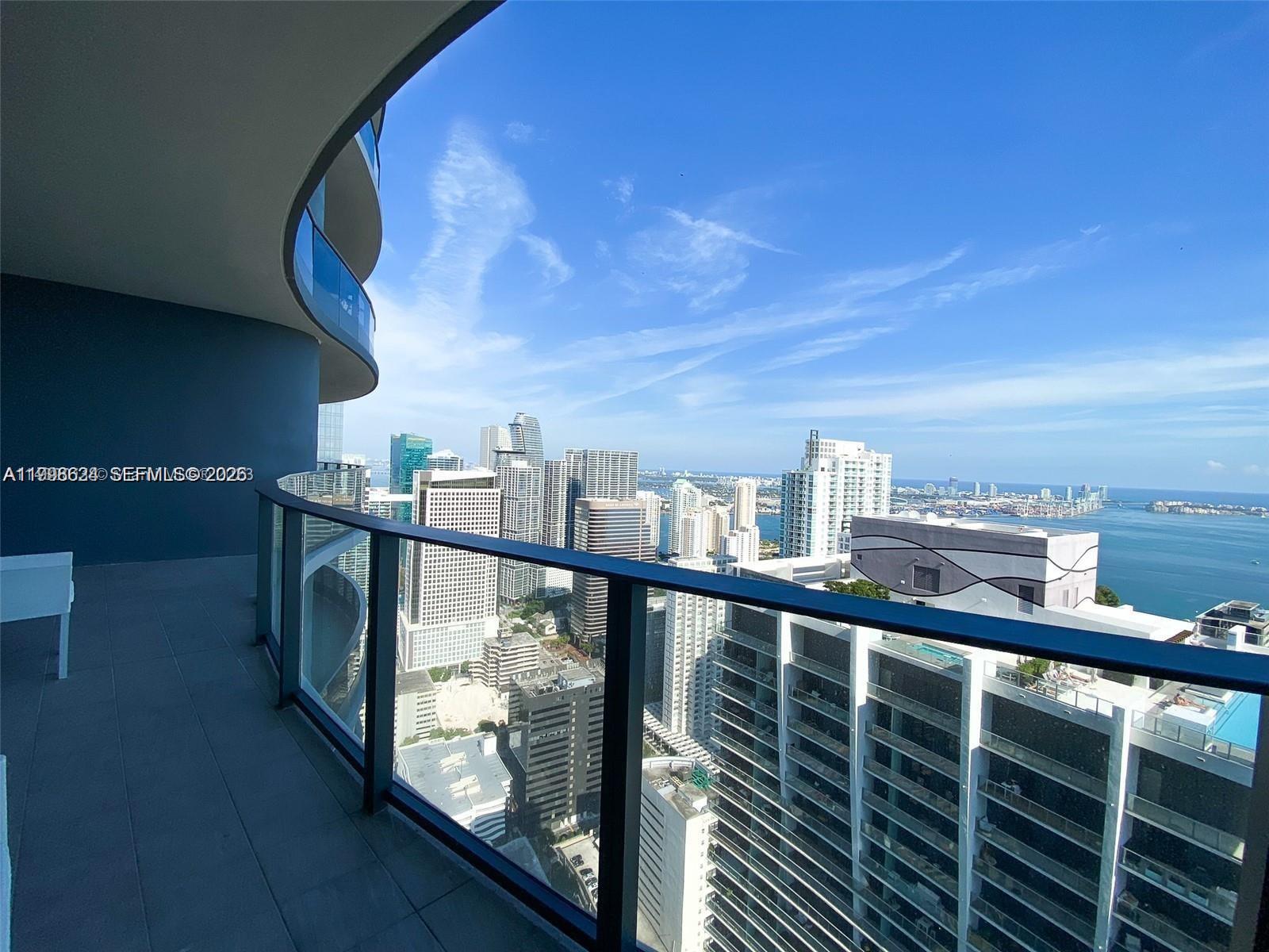 A high-rise balcony overlooks a dense city skyline and a large body of water — 1000 Brickell Plz, Miami FL 33131, MIAMI, FL