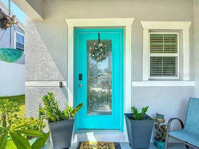 A bright turquoise front door with a glass insert and wreath sits on a porch — 2244 CANYON BREEZE AVENUE, KISSIMMEE, FL