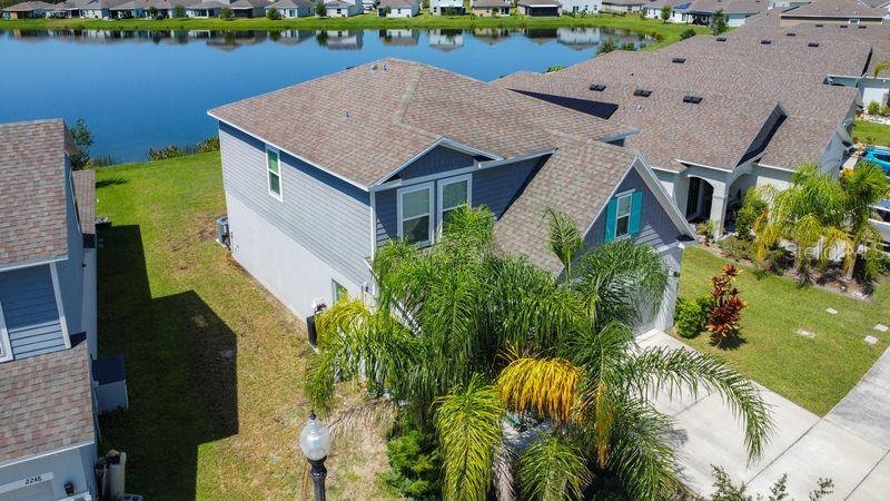 An aerial view shows a two-story house with a gray exterior next to a lake — 2244 CANYON BREEZE AVENUE, KISSIMMEE, FL