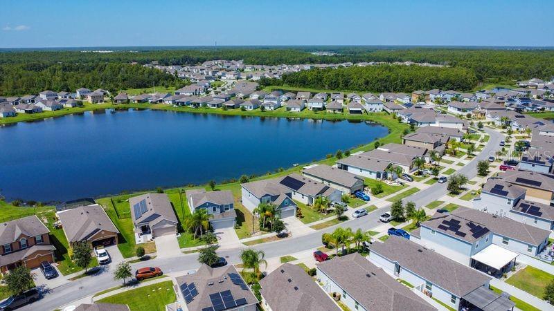 An aerial view shows a suburban neighborhood with houses surrounding a large lake — 2244 CANYON BREEZE AVENUE, KISSIMMEE, FL