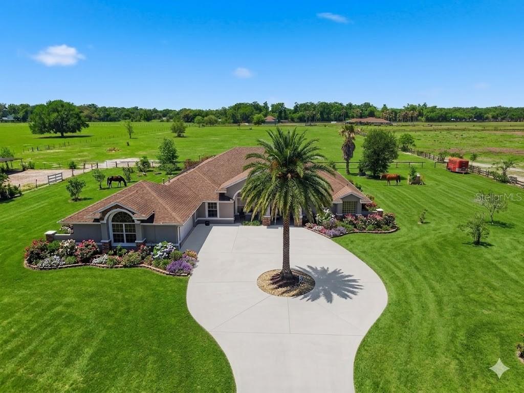 A screened-in patio features a swimming pool with a waterfall and lounge chairs — 12764 COUNTY ROAD 223, OXFORD, FL