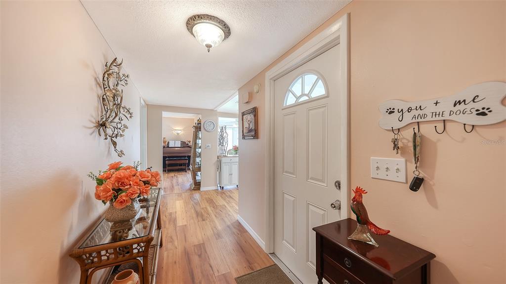 An entryway features a white front door, wood-look flooring, and a console table with flowers — 2623 RIVERBLUFF PARKWAY UNIT V144, SARASOTA, FL