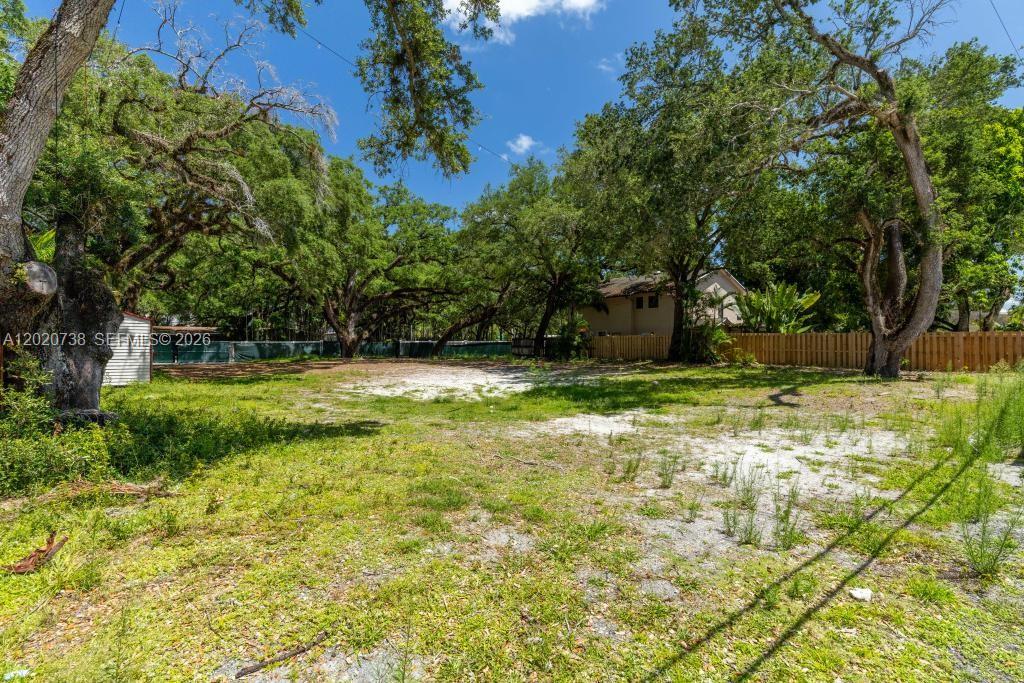 A vacant, grassy lot is surrounded by mature trees and a wooden fence — 5941 SW 36th Ter, Dania Beach FL 33312, DANIA BEACH, FL