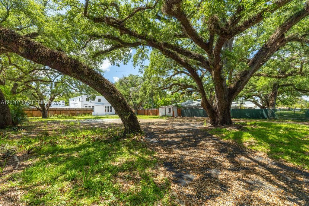 A large, shaded backyard features mature oak trees, a gravel driveway, and a small shed — 5941 SW 36th Ter, Dania Beach FL 33312, DANIA BEACH, FL