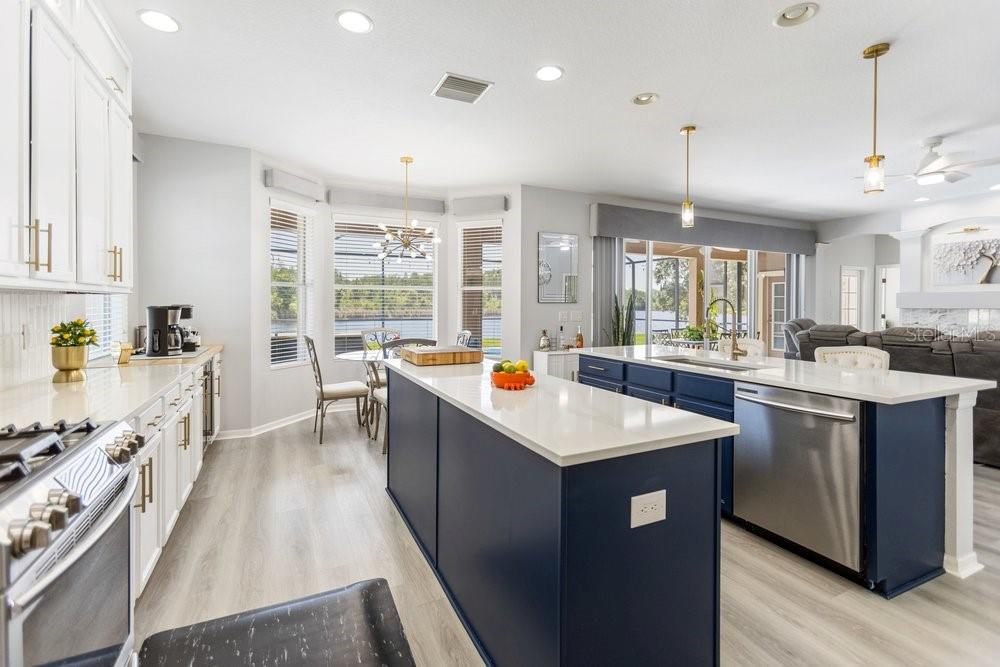 A kitchen with white cabinets, a navy blue island, and light wood-look flooring — 8758 CRYSTAL CREEK COURT, LAND O LAKES, FL