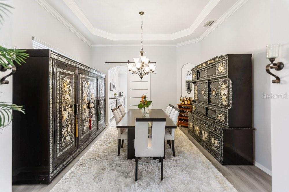 A formal dining room features a long table, chairs, and ornate black cabinets — 8758 CRYSTAL CREEK COURT, LAND O LAKES, FL