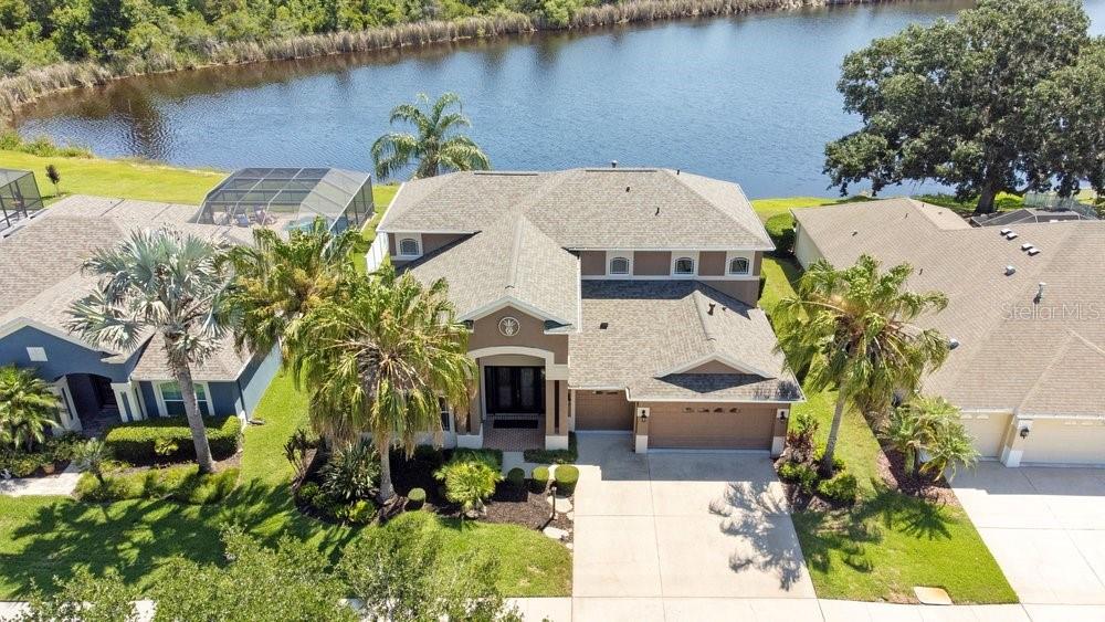 An aerial view of a two-story house with a garage, palm trees, and a lake — 8758 CRYSTAL CREEK COURT, LAND O LAKES, FL