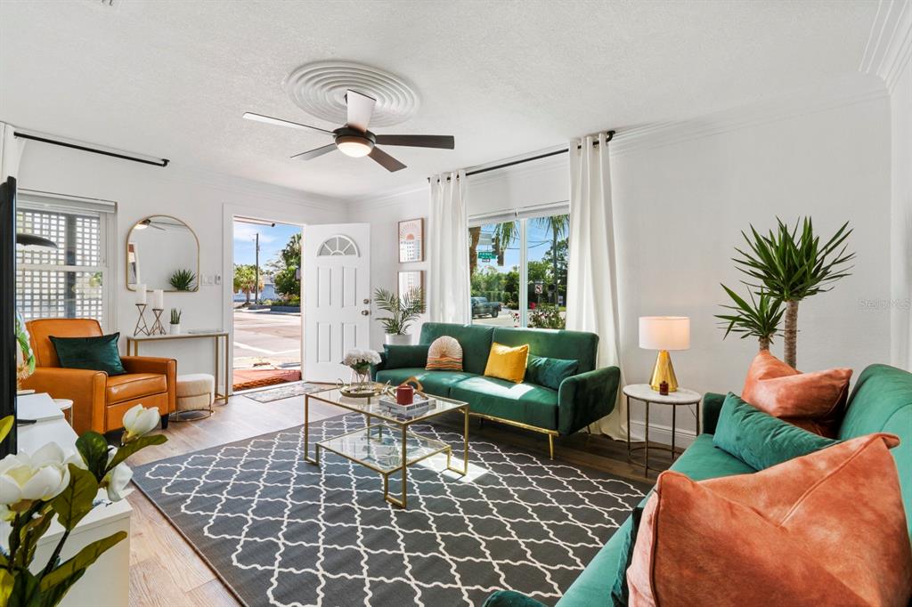 A living room features a green sofa, an orange armchair, and a patterned area rug — 2402 W CYPRESS STREET, TAMPA, FL