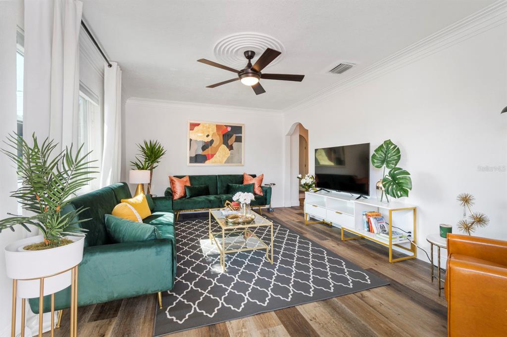 A living room features two green velvet sofas, a patterned rug, and a television console — 2402 W CYPRESS STREET, TAMPA, FL