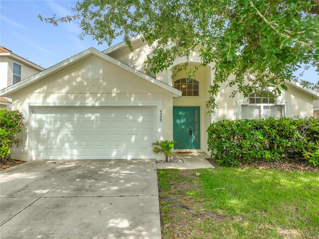 A single-story house with a white garage, teal front door, and a large tree — 5373 TORTUGA DRIVE, ORLANDO, FL