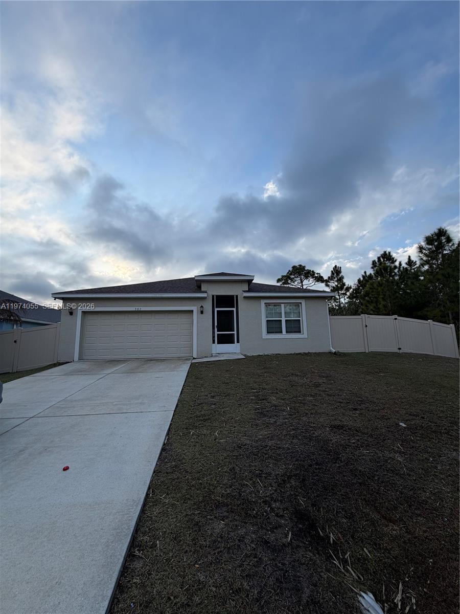 A single-story house with a beige exterior, a two-car garage, and a white vinyl fence — 383 Hanford Road SW, Palm Bay FL 32809, PALM BAY, FL