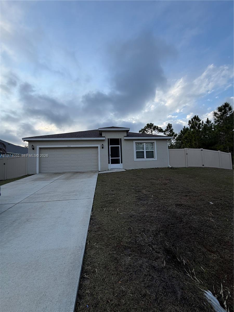 A single-story house with a beige stucco exterior, a two-car garage, and a fenced yard — 383 Hanford Road SW, Palm Bay FL 32809, PALM BAY, FL
