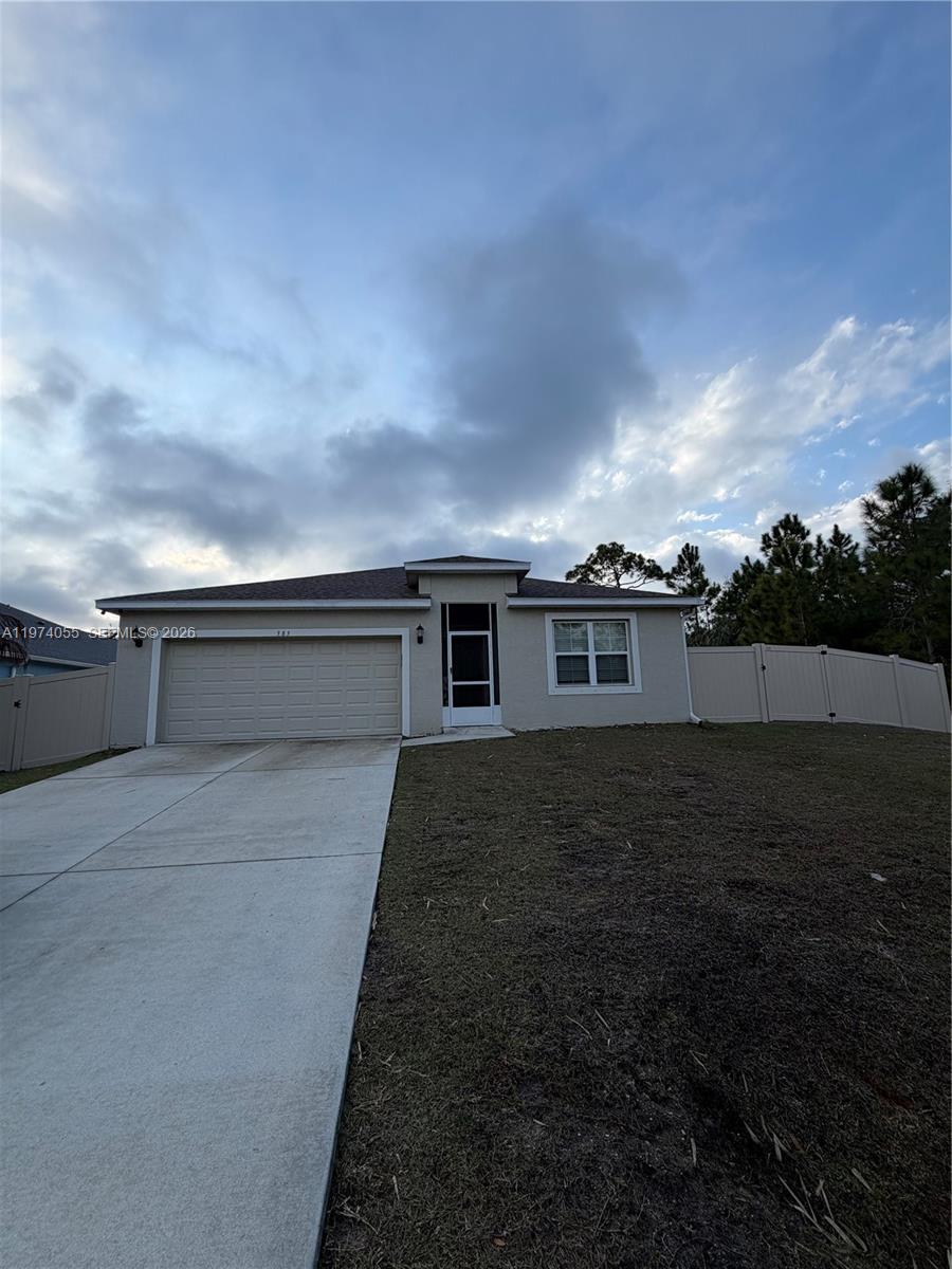 A single-story house with a beige exterior, a two-car garage, and a fenced yard — 383 Hanford Road SW, Palm Bay FL 32809, PALM BAY, FL