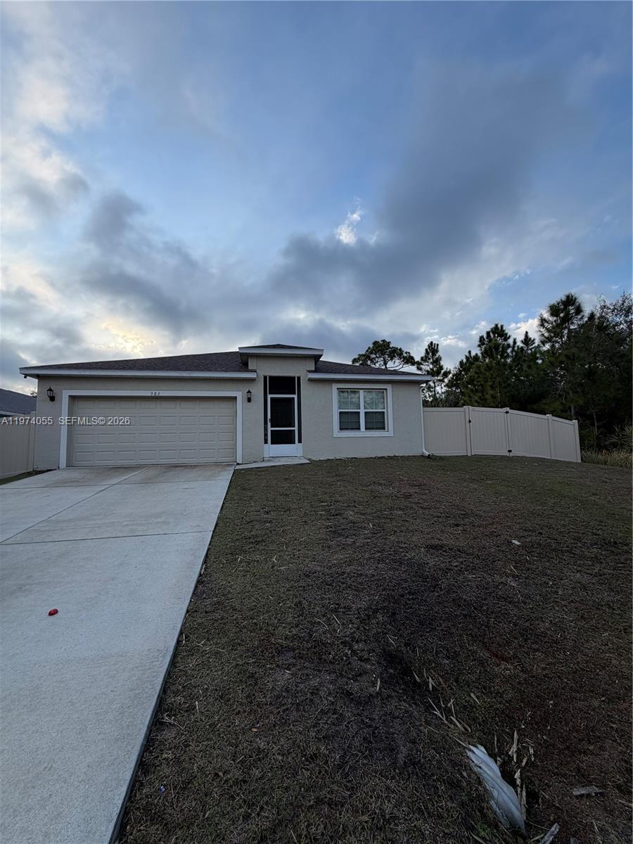 A single-story house with a beige exterior, a two-car garage, and a fenced yard — 383 Hanford Road SW, Palm Bay FL 32809, PALM BAY, FL