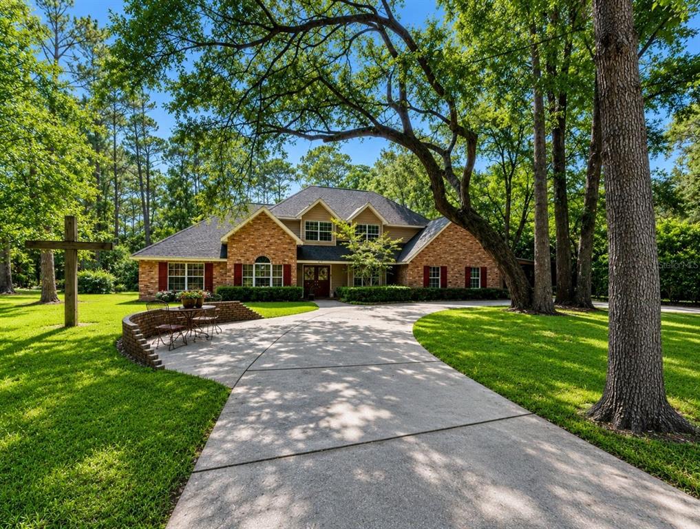 A two-story brick house with a circular driveway, red shutters, and large oak trees — 44131 PARKWAY LANE, ALTOONA, FL
